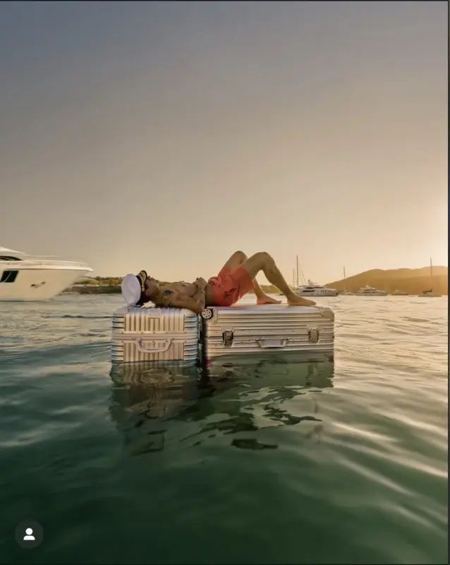 A captain laying on two suitcases floating in the water