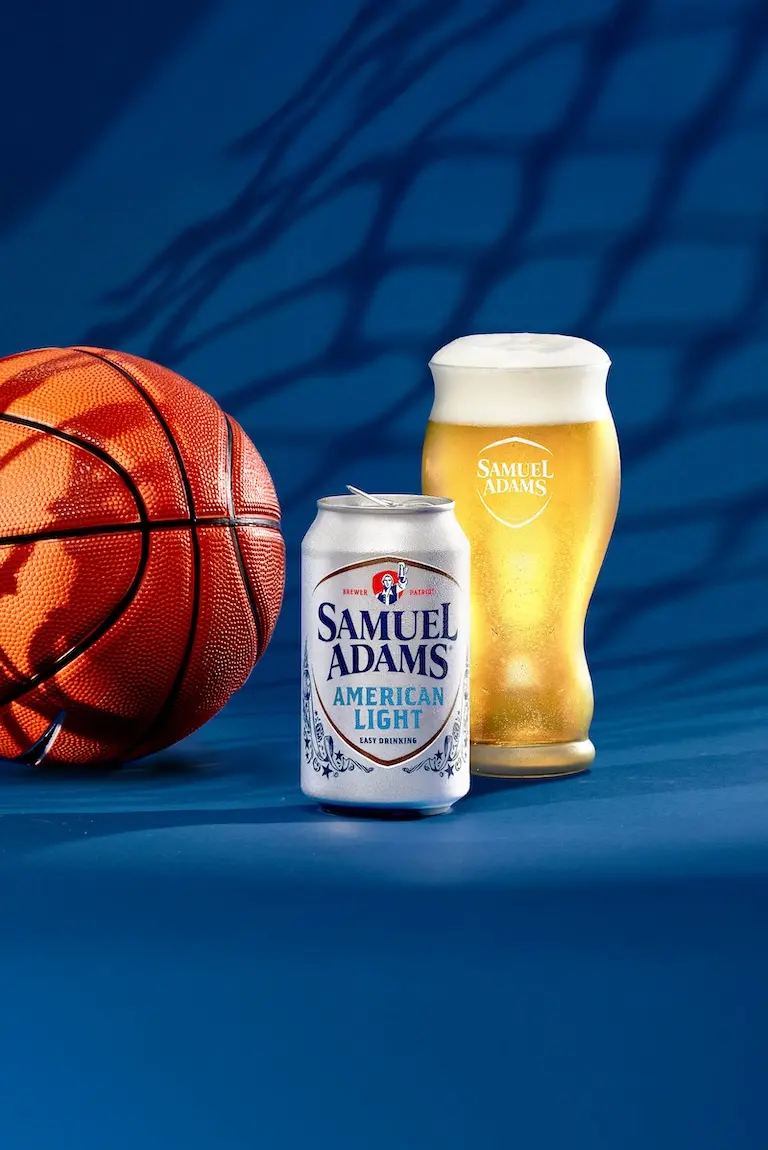 A can and glass of Samual Adams American light lager next to a basketball